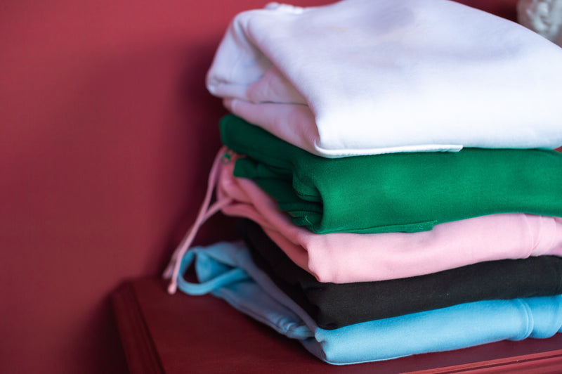 Stack of folded colorful shirts on a red surface
